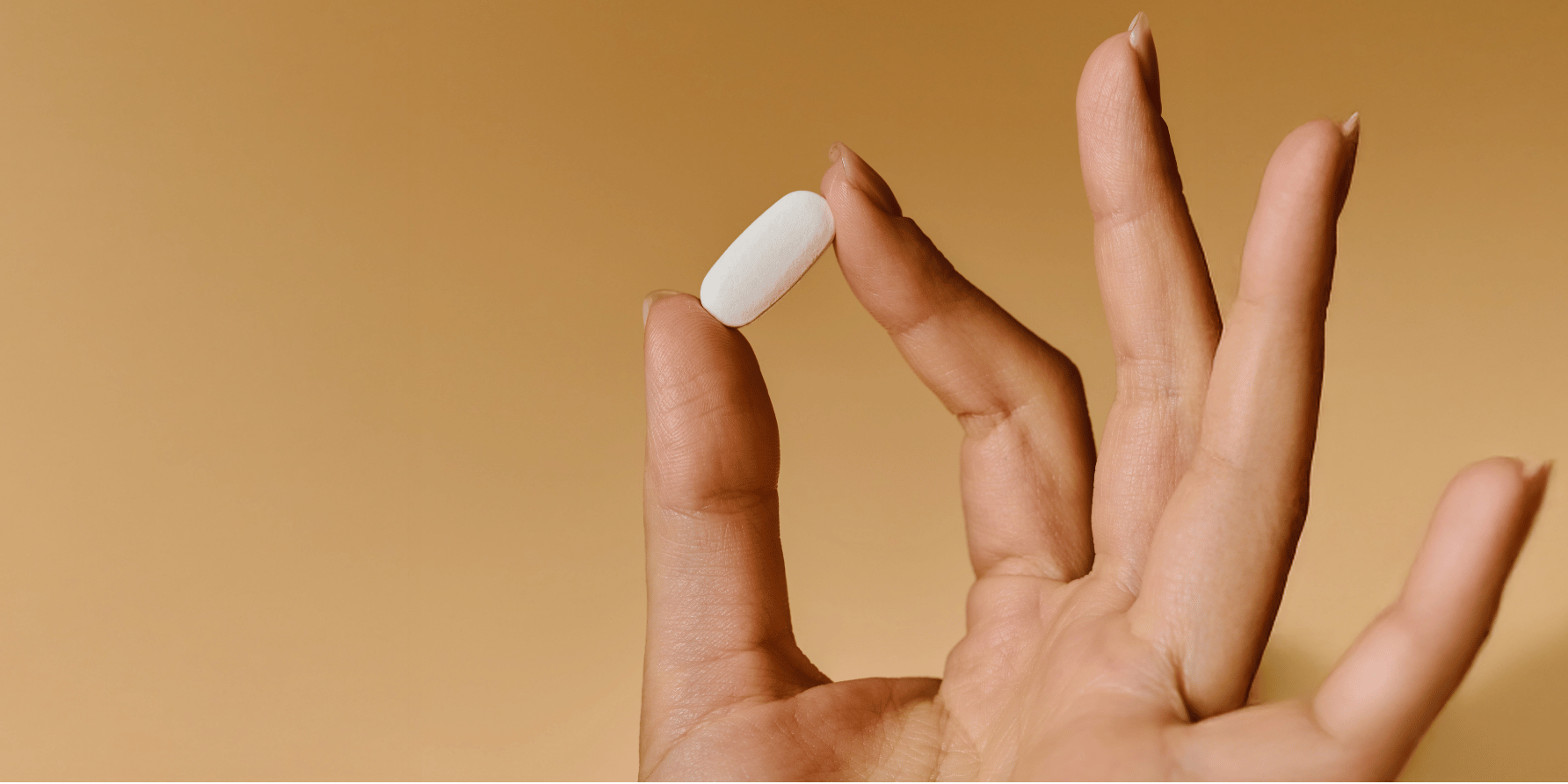 Hand on orange background holding Solgar hair, nail and skin supplement