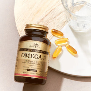 Solgar Double Strength Omega-3 Softgels in a glass bottle on a table