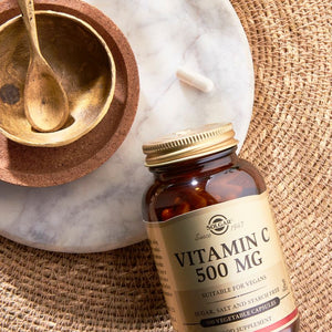 Solgar Vitamin C 500mg capsules on a table next to a wooden bowl