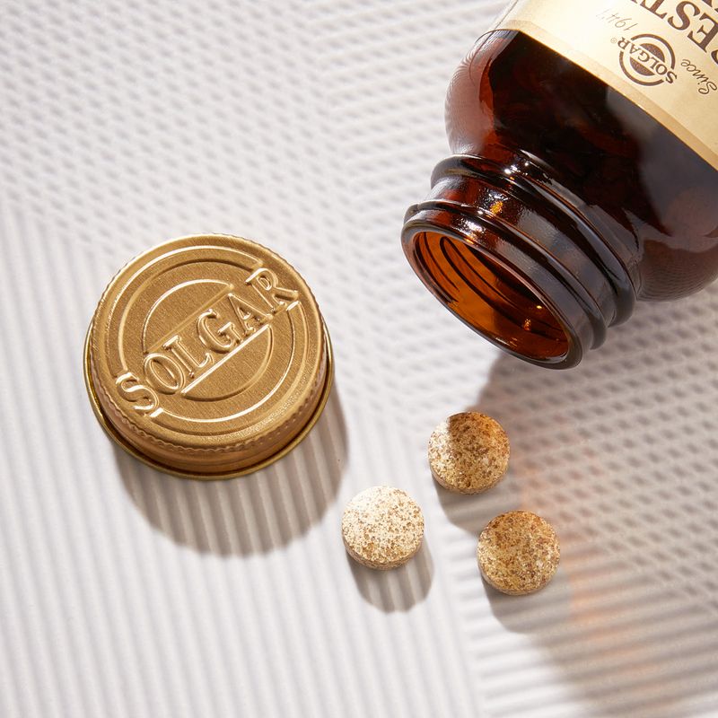 Solgar Digestive Enzymes Tablets in a glass bottle pouring onto a table