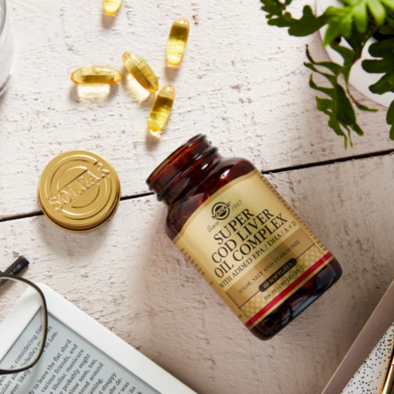 Solgar Super Cod Liver Oil Complex softgels in a glass bottle on a wooden table