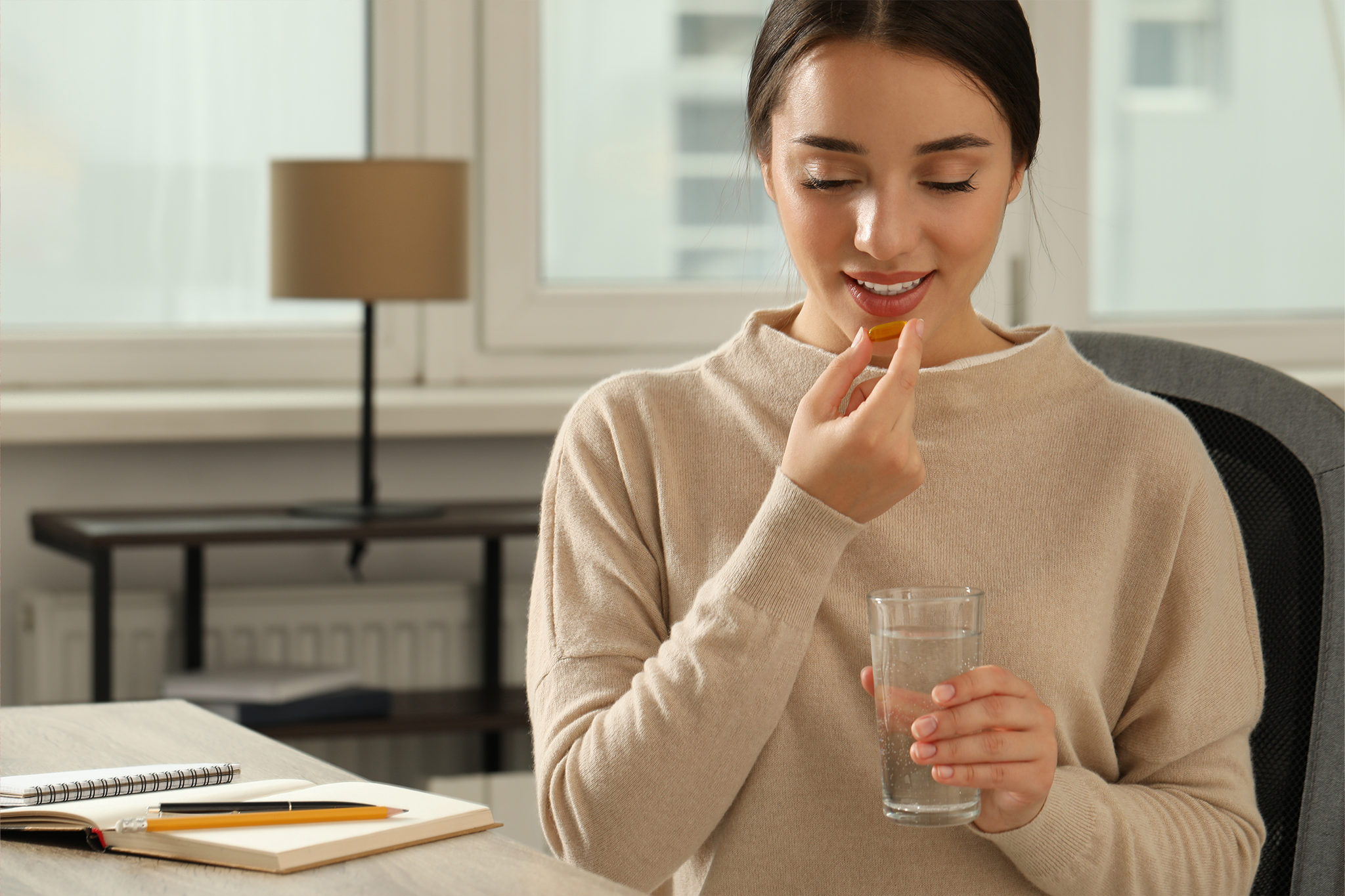 Woman having a multivitamin holding a glass of water