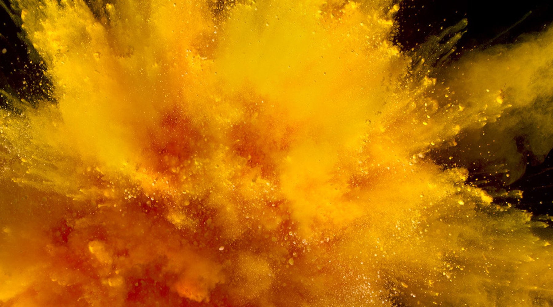 Burst of bright yellow and orange Solgar powder exploding against a dark background