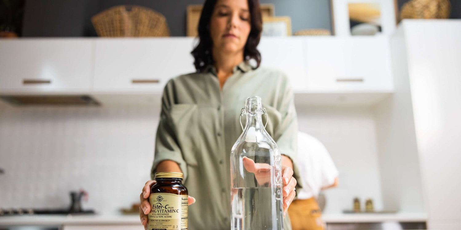 Woman in her kitchen with Solgar Ester-C tablets and a glass of water