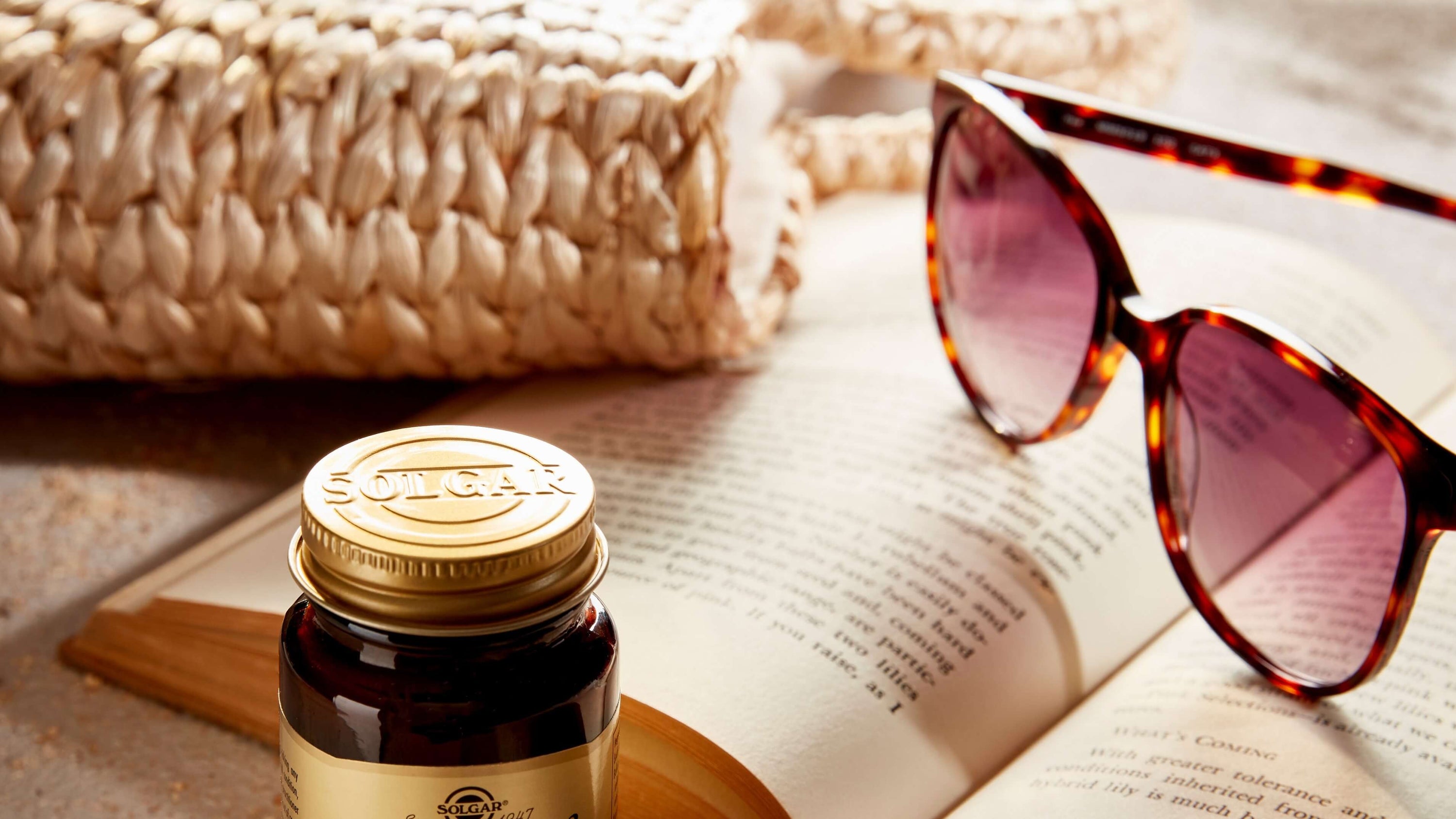 Solgar Vitamin D3 Tablets with a book and sunglasses on a table