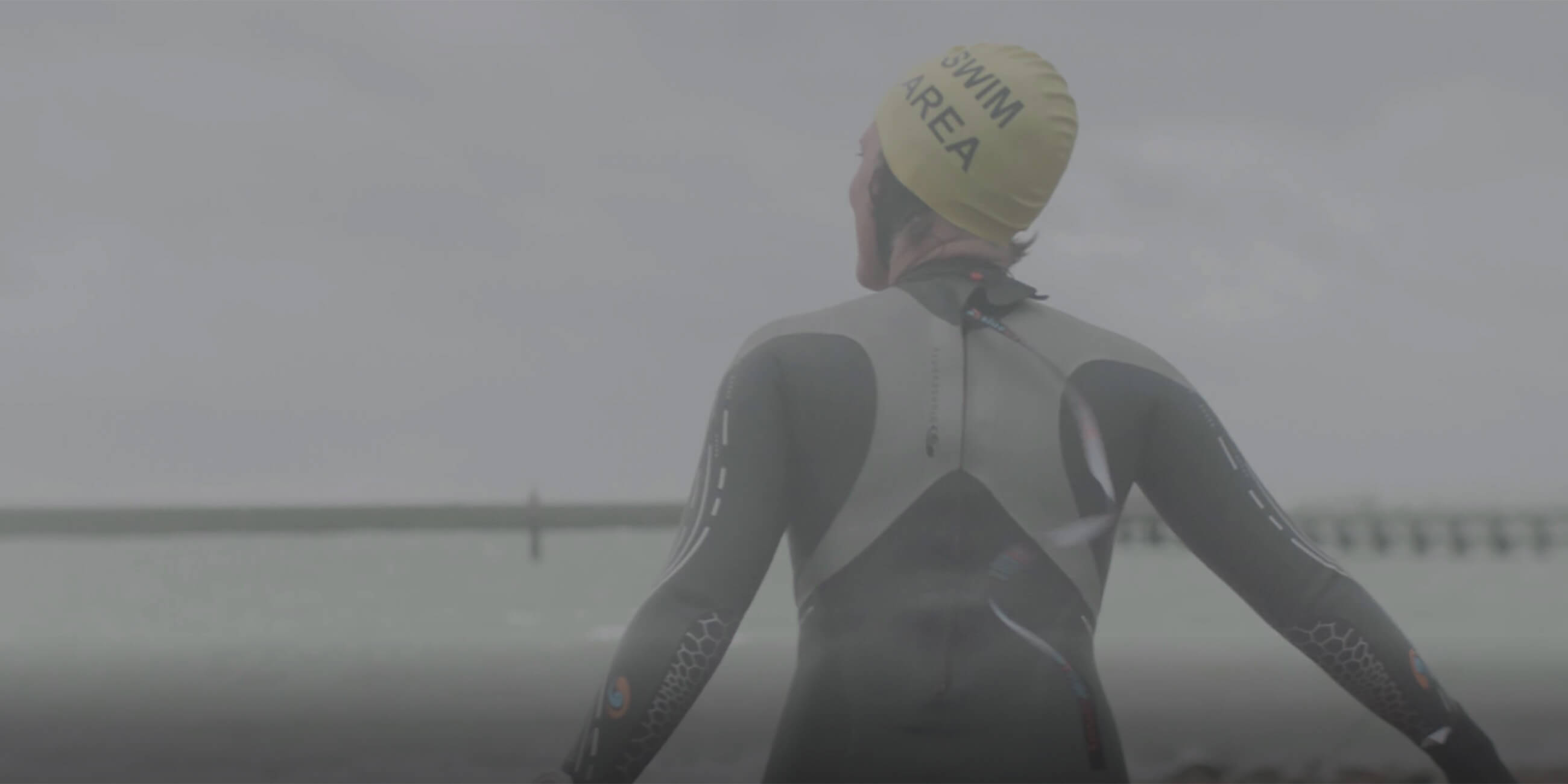 Wild Water Swimmer Louise Edmunds, a Solgar buyer running towards the sea wearing a wetsuit