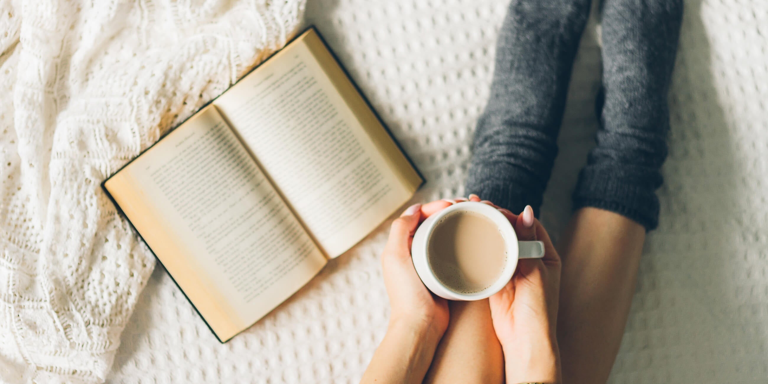 Woman on her sofa with a cup of tea and book
