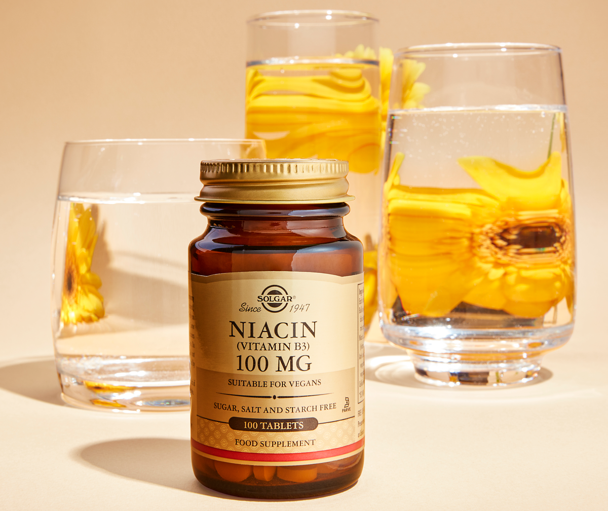 Solgar Niacin Tablets alongside yellow flowers in water 