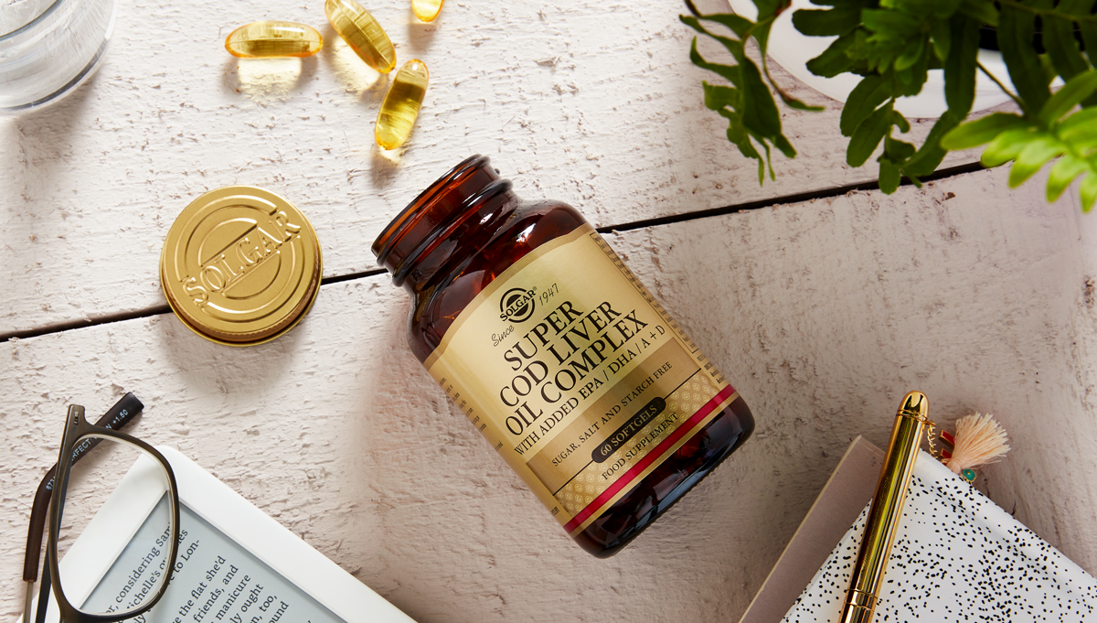 Solgar Super Cod Liver Oil Complex Tablets on a wooden table with a notepad