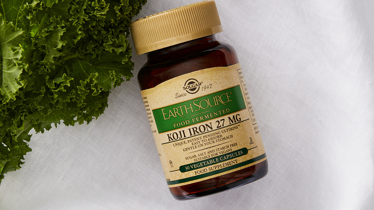 Solgar Koji Iron Supplements against a linen background next to some lettuce