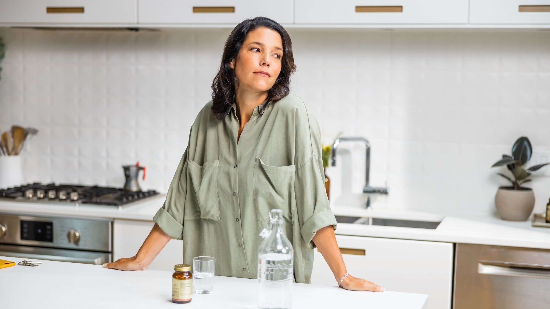 Woman in her kitchen with Solgar Amino Acid supplements on her table next to a glass of water