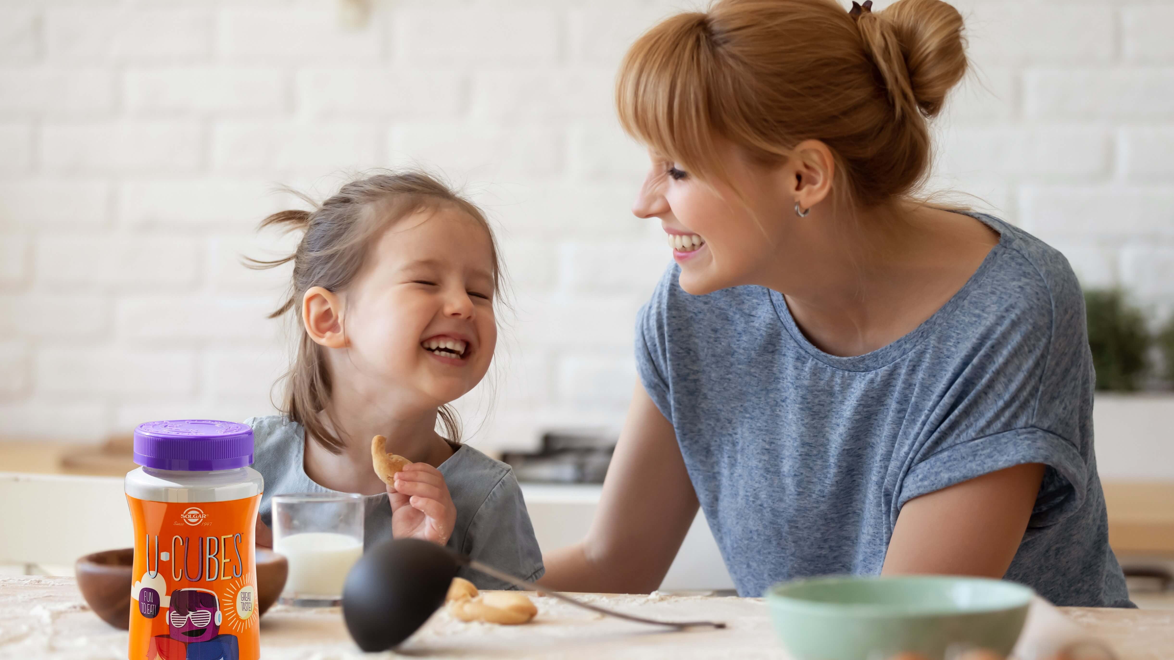Women and daughter smiling eating breakfast with a glass of milk in their kitchen