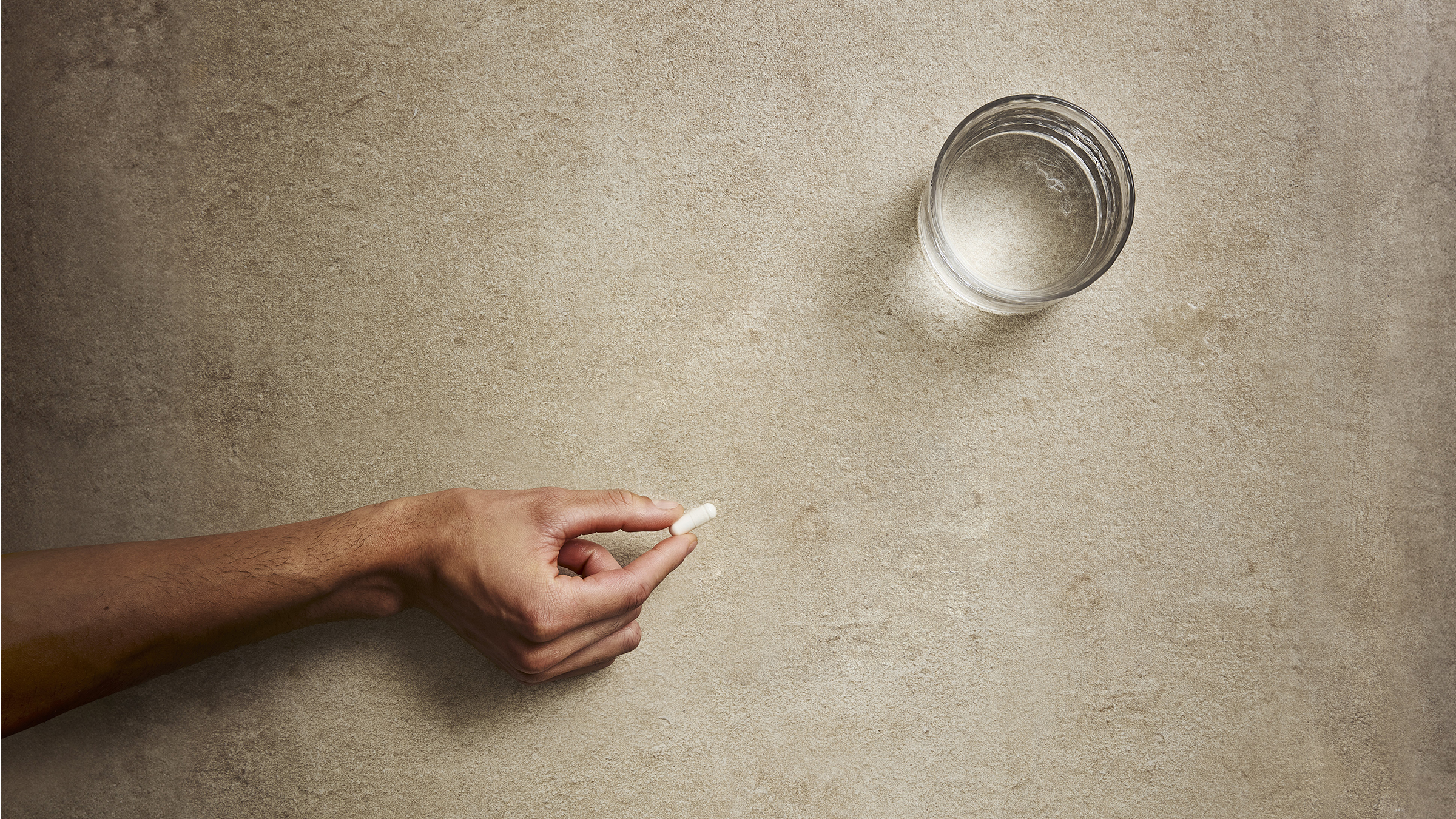 Solgar Magnesium tablet on a stone table with a glass of water