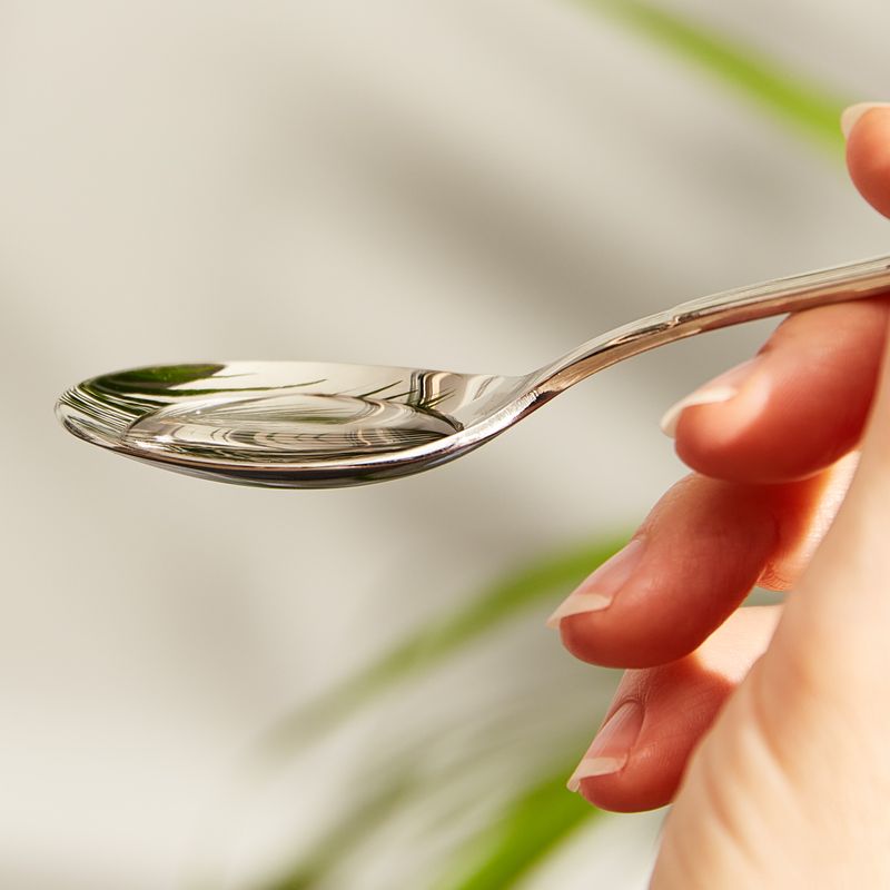 Metal spoon containing Solgar L-Carnitine 1500 mg Liquid in a 473 ml 
