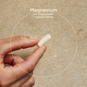 Hand holding a Solgar Magnesium Glycinate white capsule with text about magnesium.