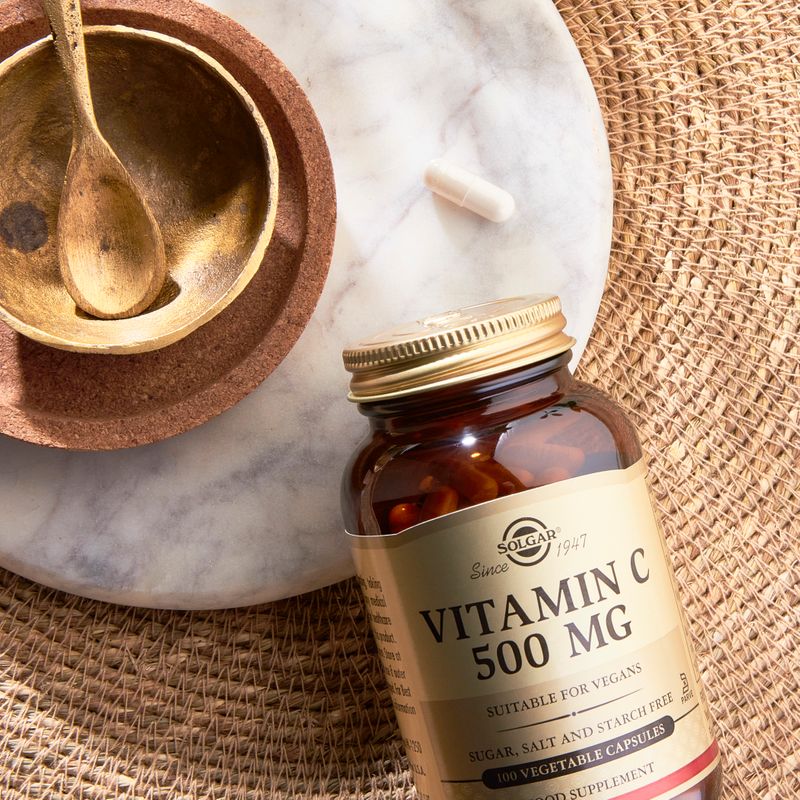 Solgar Vitamin C 500mg capsules on a table next to a wooden bowl