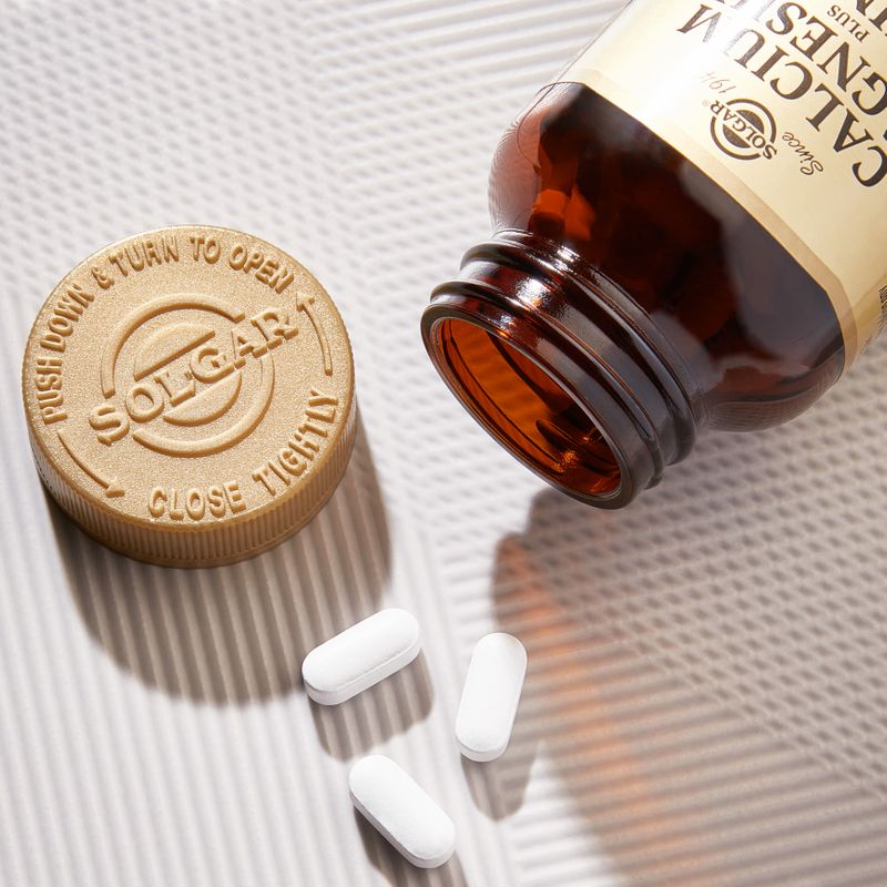 Solgar Calcium Magnesium Plus Zinc supplements in a glass bottle on a table