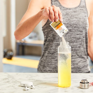 Solgar Ester C-Plus powder sachets being poured into a bottle of water