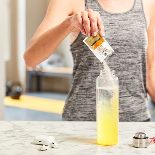 Solgar Ester C-Plus powder sachets being poured into a bottle of water