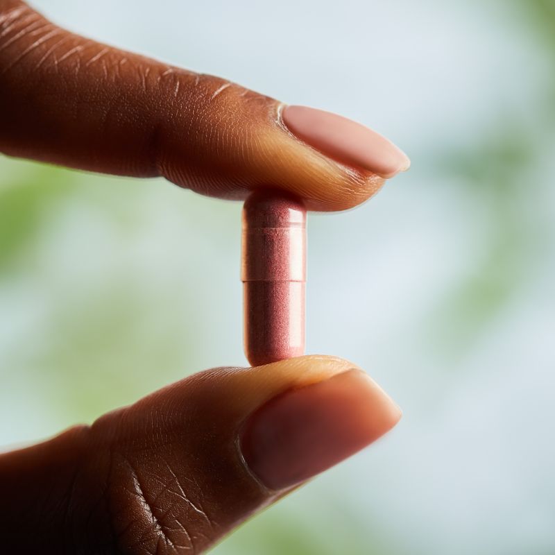 Solgar Natural Cranberry with Vitamin C vegetable capsule in a person's hand
