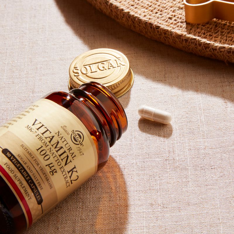 Solgar Natural Vitamin K2 MK-7 from Natto Extract vegetable capsules in a glass bottle on a table