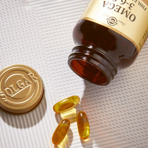 Solgar Omega 3-6-9 Fish Oil glass bottle on a table with tablets beside it