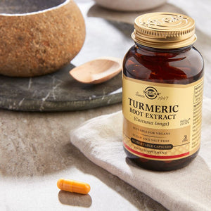 Solgar Turmeric Root Extract vegetable capsules in a glass bottle on a marble table