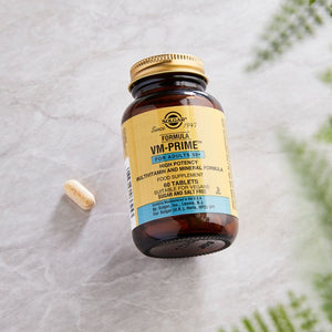Solgar VM-PRIME multivitamin tablets in a glass bottle on a marble table