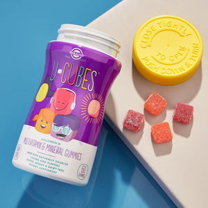 Solgar U-Cubes Children's Multi-Vitamin and Mineral Gummies bottle on a table with some loose gummies alongside