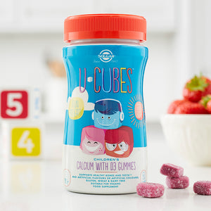 Bottle of Solgar U-Cubes children gummies on a table with some loose gummies beside it